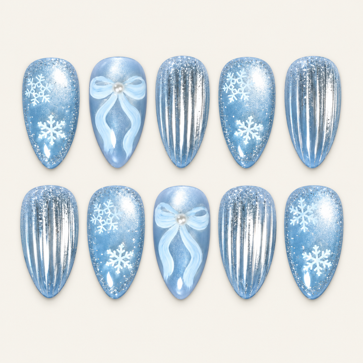 Ten icy blue press-on nails arranged in two rows on a light greige background, featuring white snowflakes, pale blue bows, and silver vertical stripes.