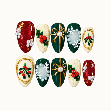 Ten Christmas press-on nails arranged in two rows on a light neutral background, featuring red sparkle, ivory berry sprigs, green gold-bow accents, snowflakes, and pearl-like details.