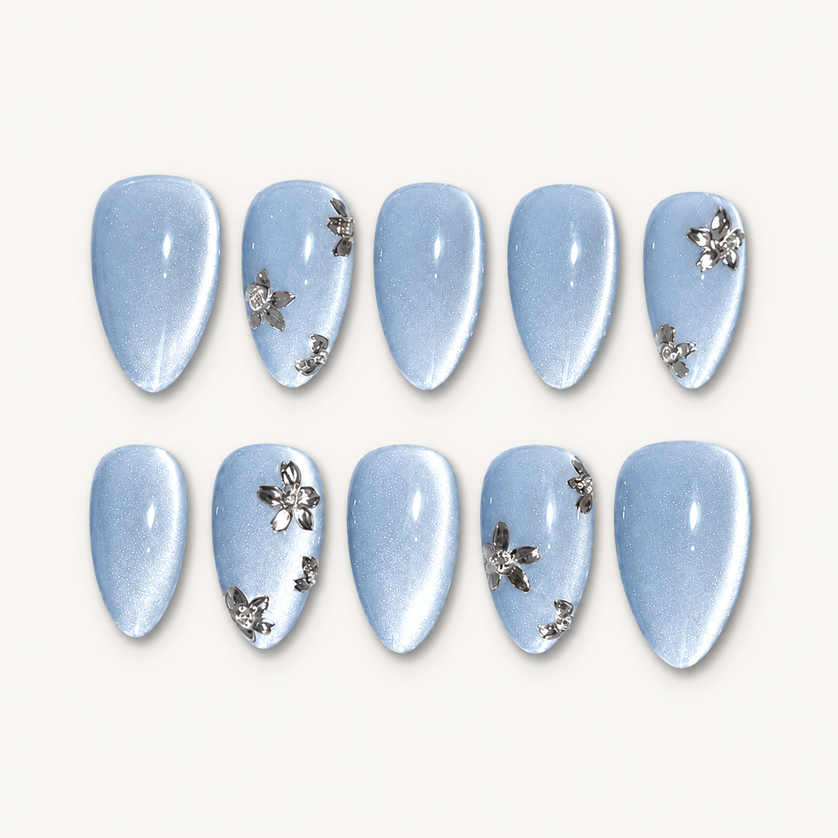 Ten pale blue shimmer nails arranged in two rows on an off-white background, with silver-toned flowers on select nails.