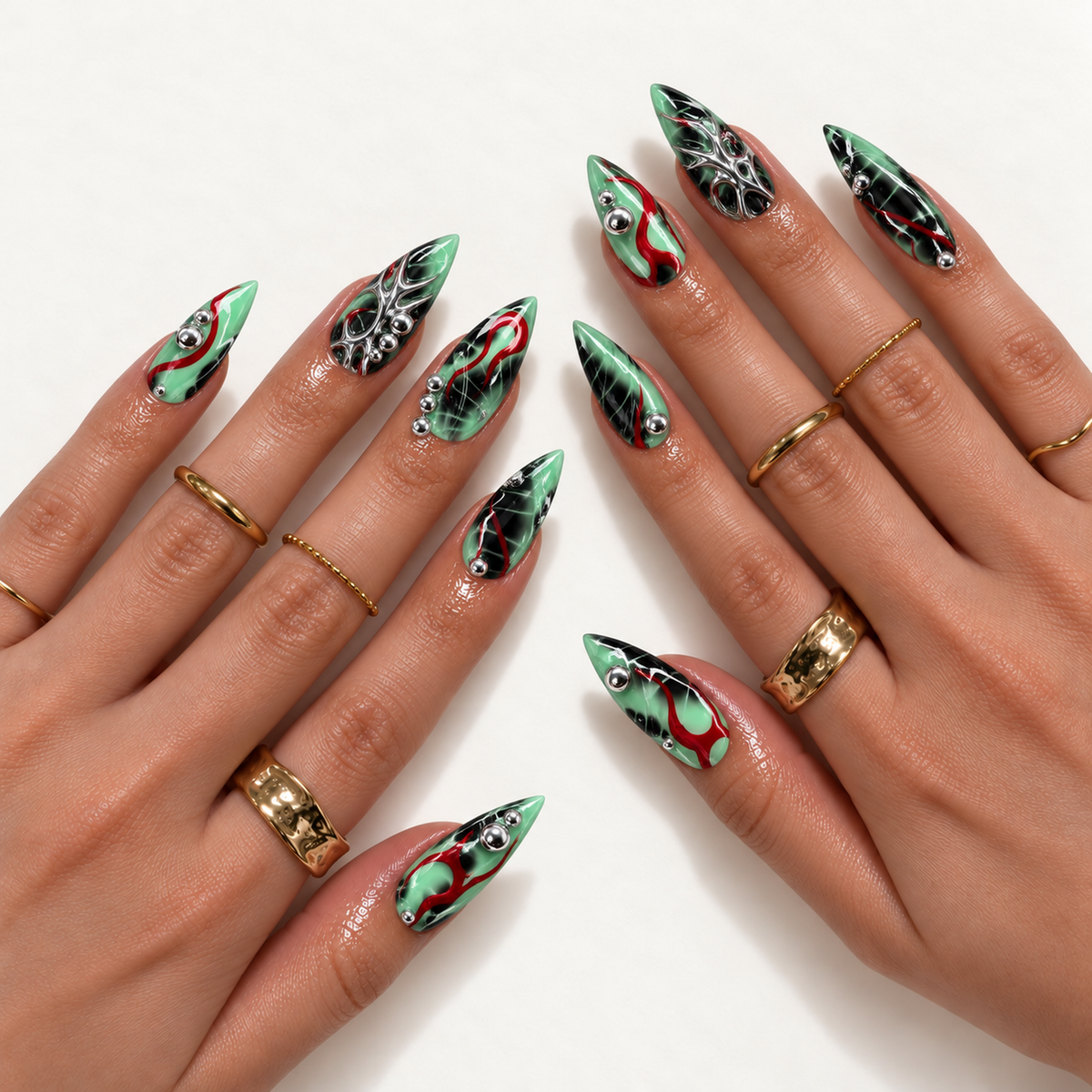 Hand model mockup showing mint green and black pointed nails with red ribbons, branching silver details, and silver beads, paired with gold rings.