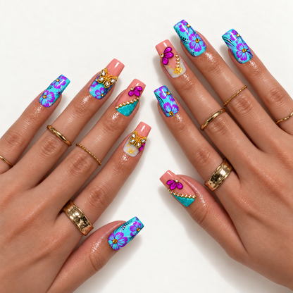 Hand mockup showing the turquoise floral and coral pink nail design with purple blooms, jeweled butterflies, raised petals, and gold-tone rings.