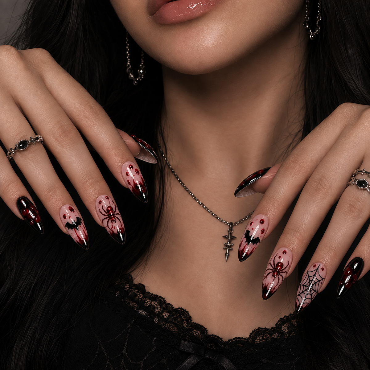 Hands wearing Crimson Web nails with black glossy tips, deep red splatter, spider, bat, and web details.