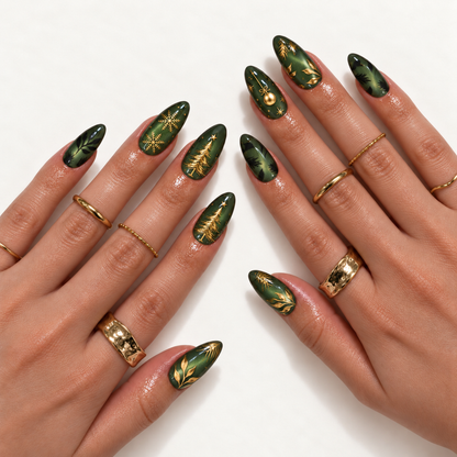 Hand model mockup showing green shimmer nails with gold-colored trees, snowflakes, an ornament, and botanical accents, styled with gold-toned rings.