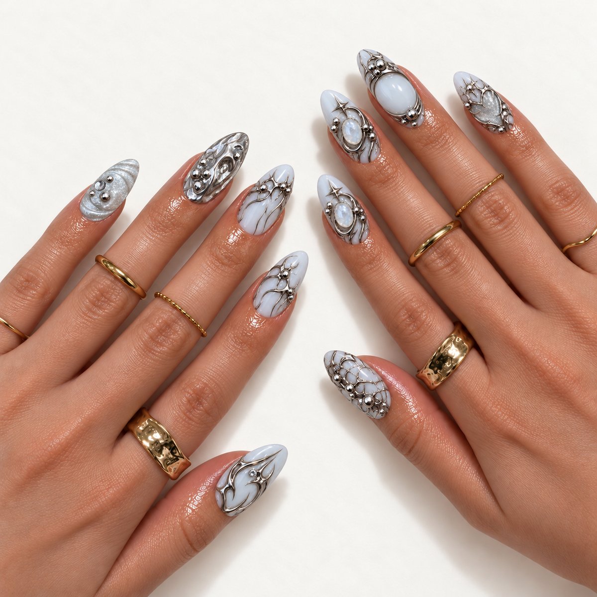 Hand model mockup showing silver and milky white nail art with chrome curves, starbursts, glitter accents, and ornamental details, styled with gold-tone rings.