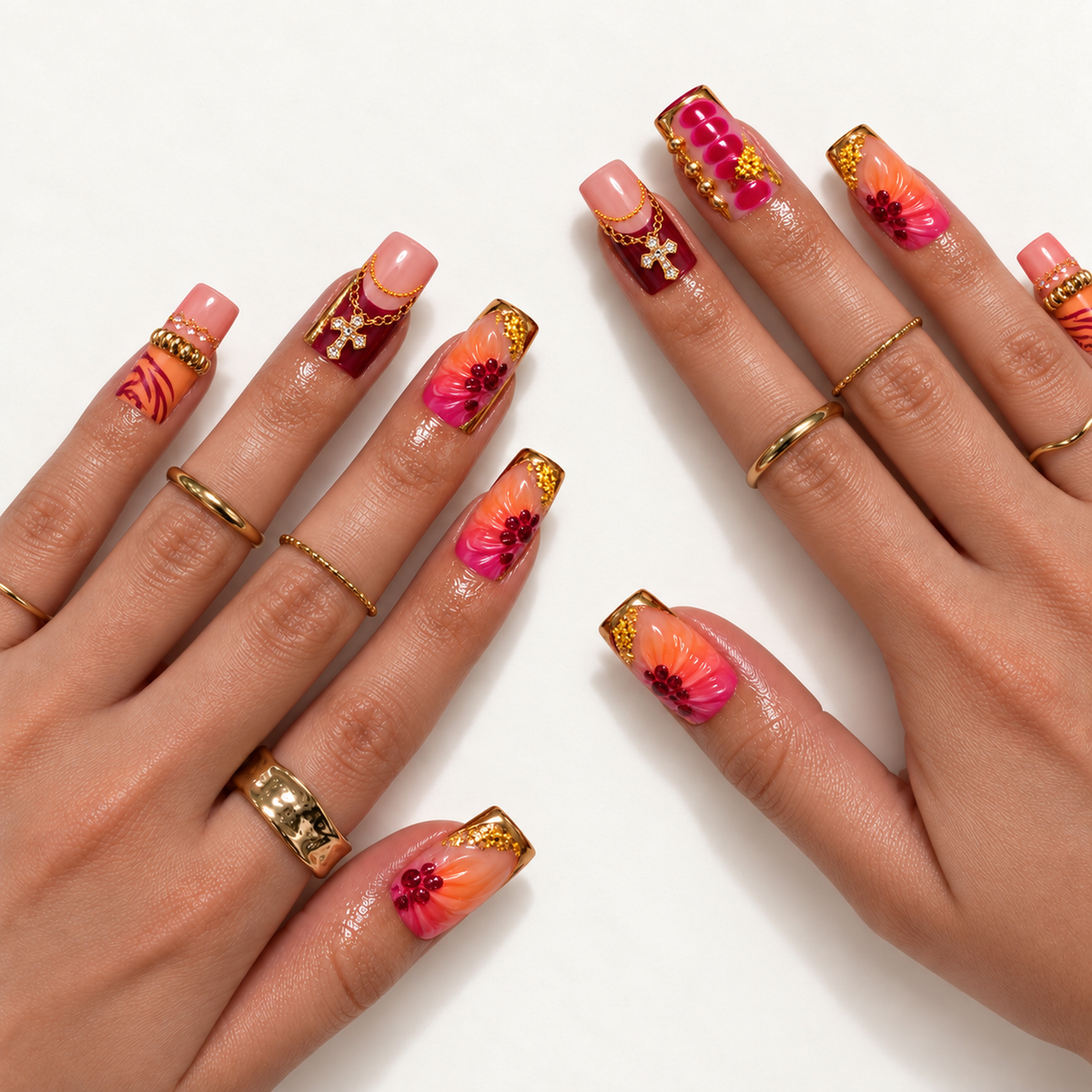 Two hands model the glossy floral design with peach-to-fuchsia petals, burgundy accents, gold-tone embellishments, and sparkling cross charms.