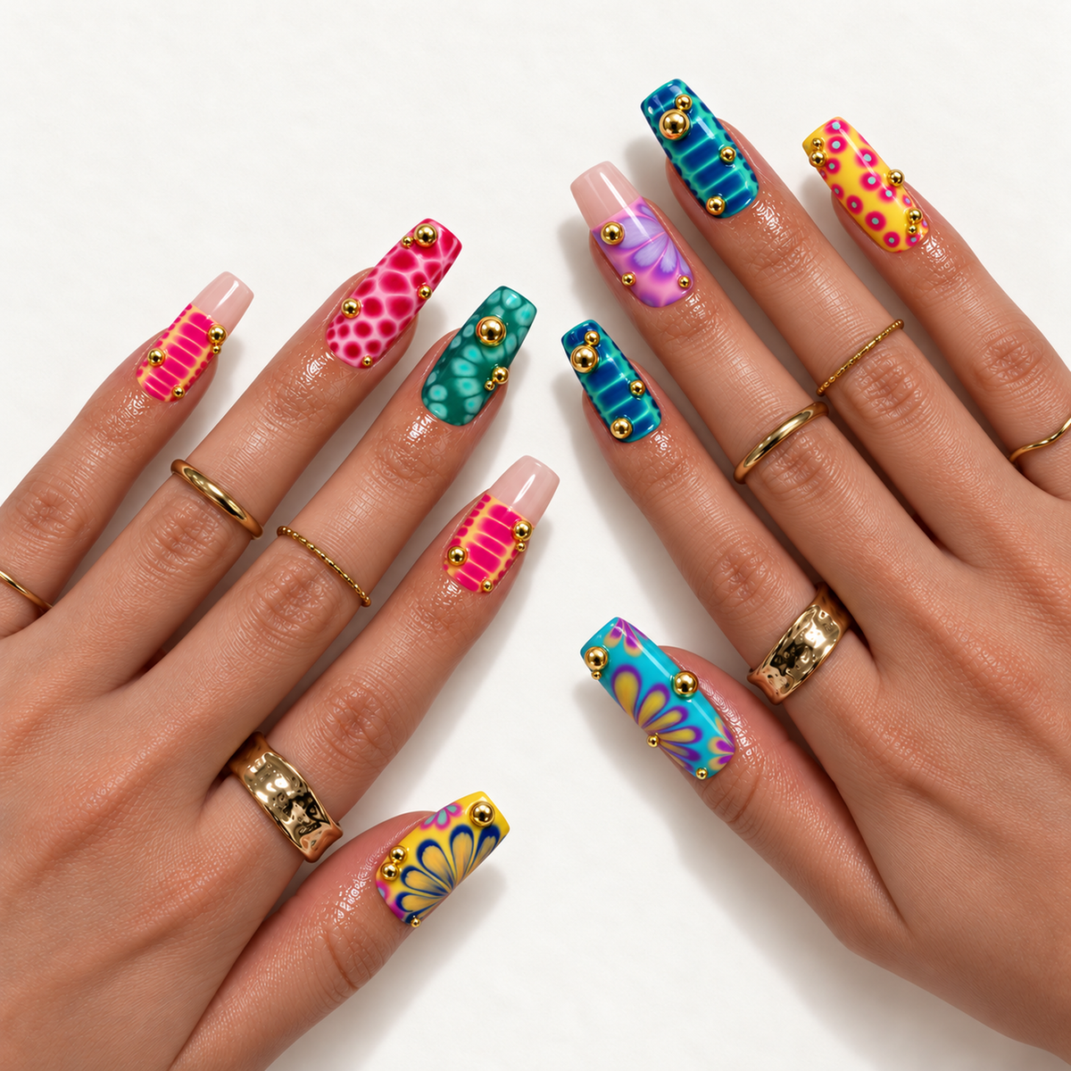 Hand model mockup showing bright mixed-pattern nails with pink, turquoise, yellow, and purple artwork, raised gold-tone accents, and gold-tone rings.