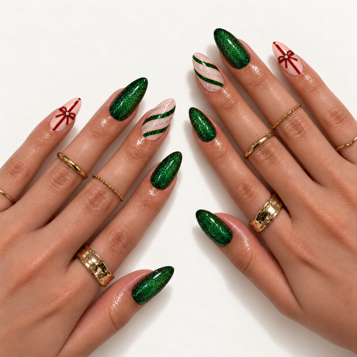 Two hands wearing tapered emerald glitter nails with blush pink bow and striped accents, styled with gold-toned rings.