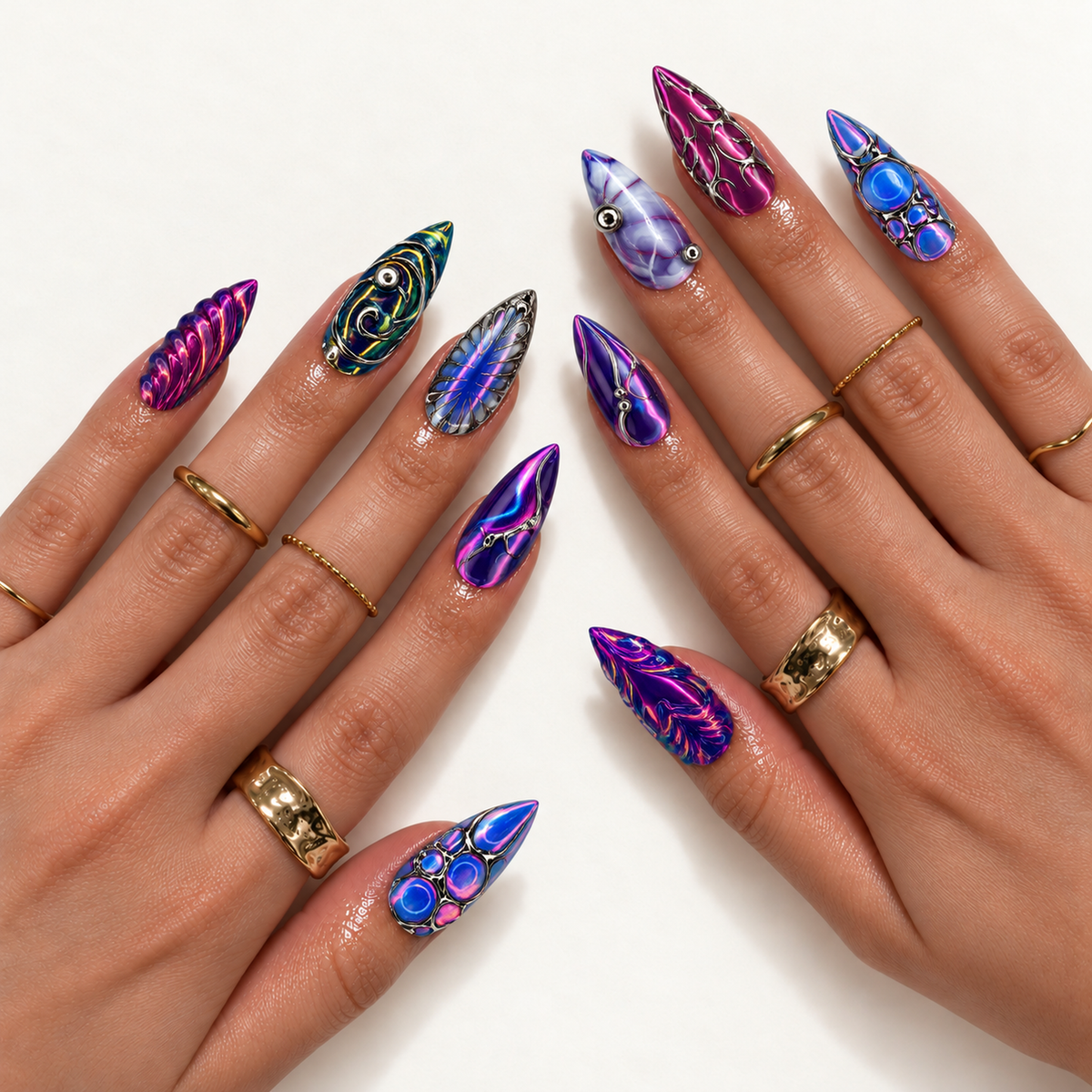 Two hands modeling pointed nails with vivid purple and blue swirls, silver-tone filigree, circular accents, and featherlike patterns, paired with gold-tone rings.