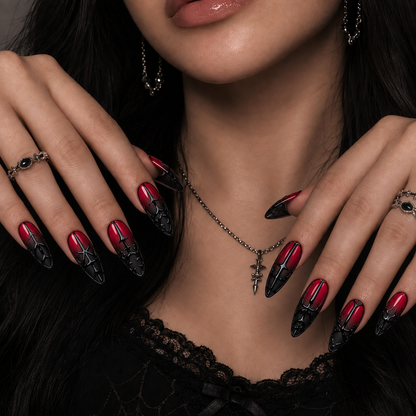 Crimson-to-black gothic press-on nails shown on a hand, featuring glossy black gate-inspired linework and ornate pointed arches.