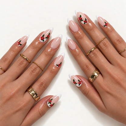 Hand model mockup showing pink shimmer French tips with red holly berries and green leaves, styled with gold rings.