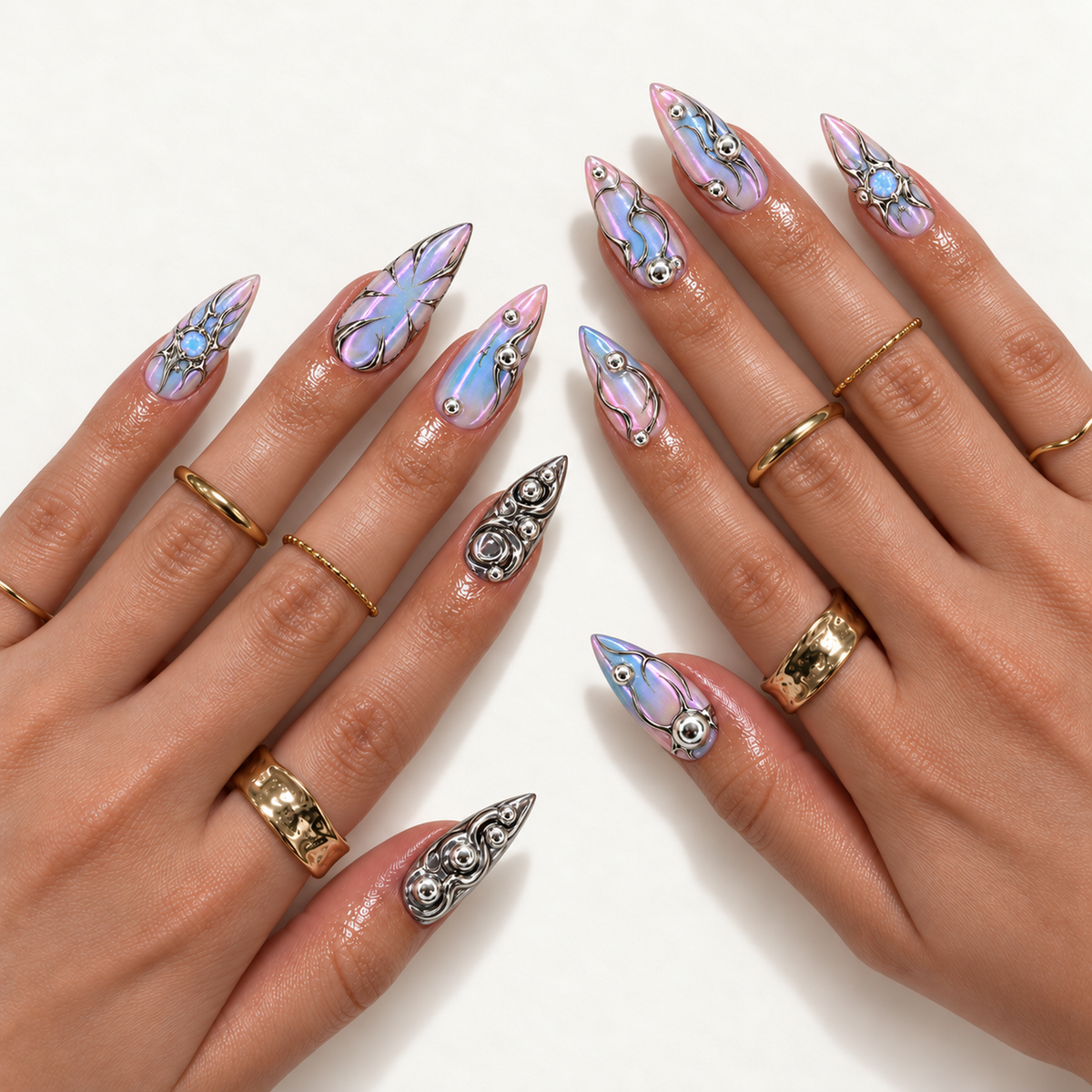 Hand model mockup showing pointed pastel iridescent nails with silver ornamental lines and metallic swirl accents, styled with gold-tone rings.