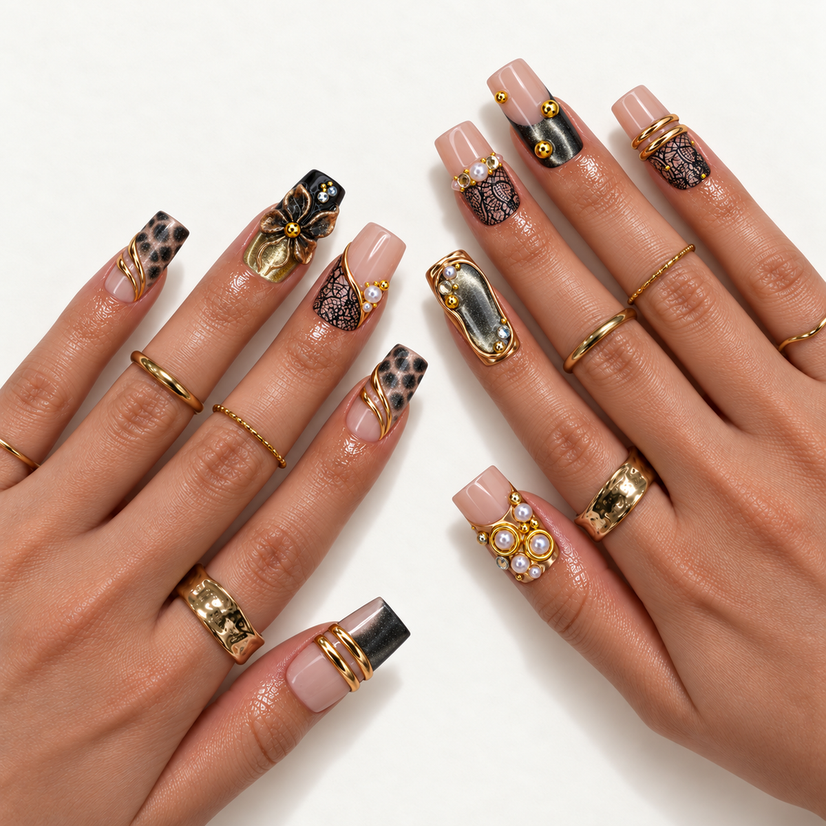 Hand-model mockup showing the nude pink and black nail design with gold-tone curves, spotted accents, a raised flower, and pearl-like embellishments.