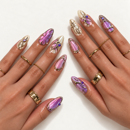 Two hands modeling pink-lilac shimmer and ivory nails with reflective metallic flourishes, purple accents, and pearl-like details.