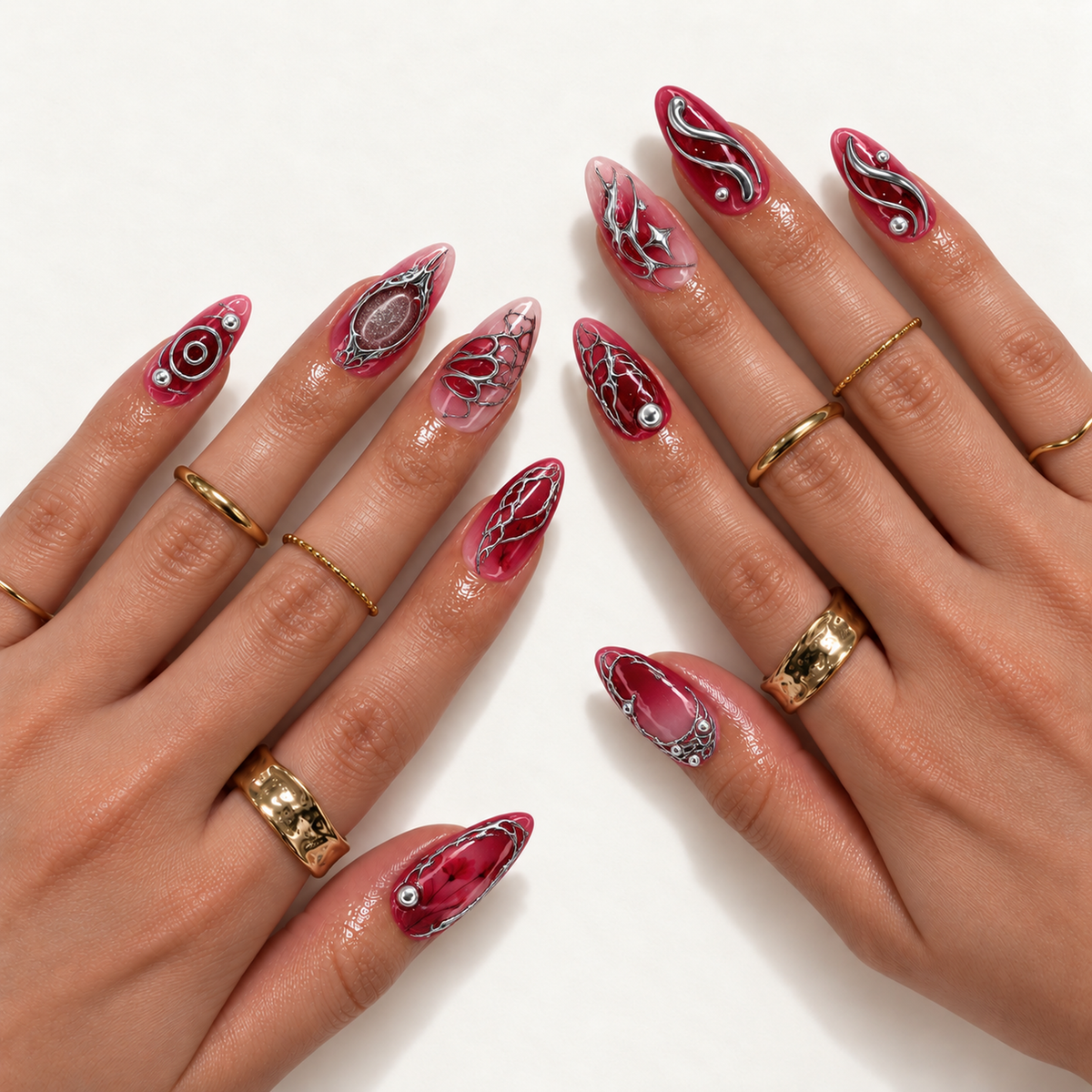 Hand-model mockup showing red and pink nails with silver-tone ornamental lines, floral details, and reflective accents, styled with gold-tone rings.