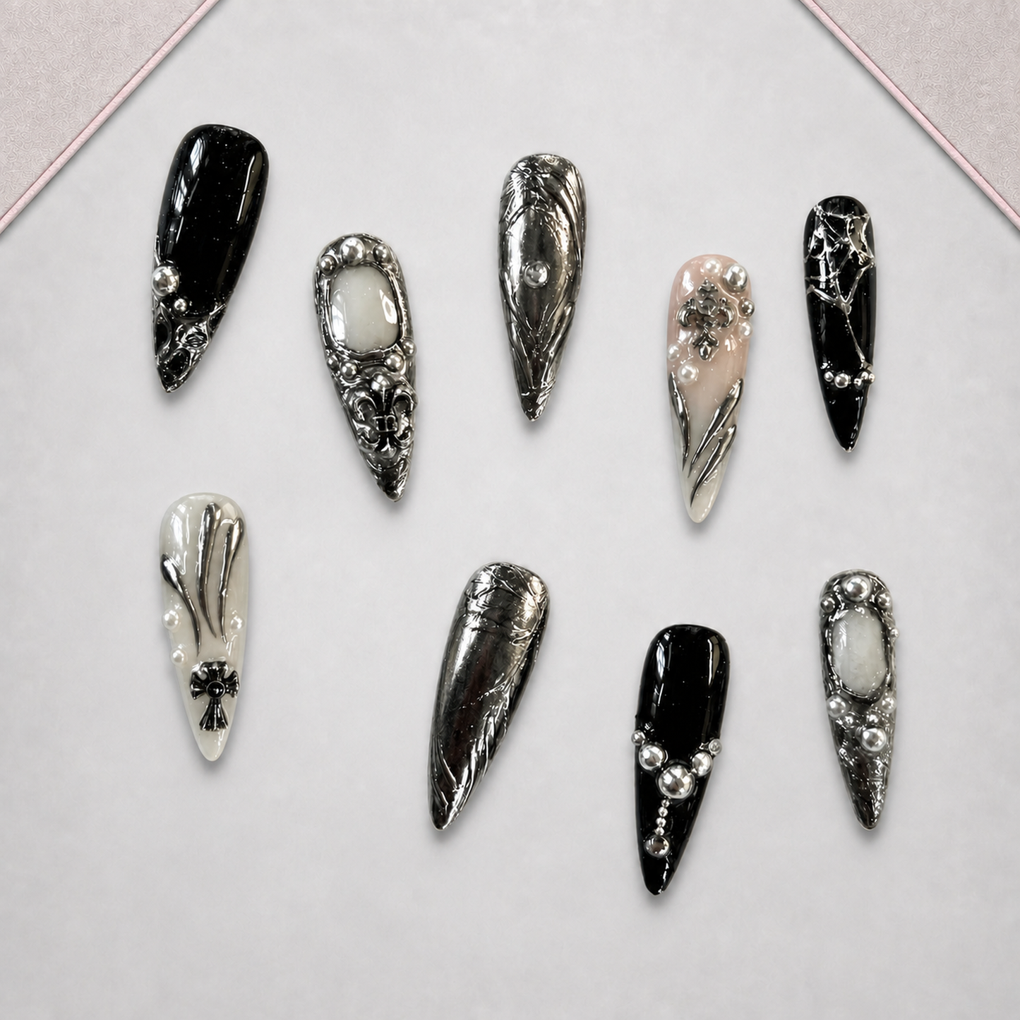 Chrome Reliquary press-on nail set arranged on a display tray with glossy black and ornate silver gothic designs.