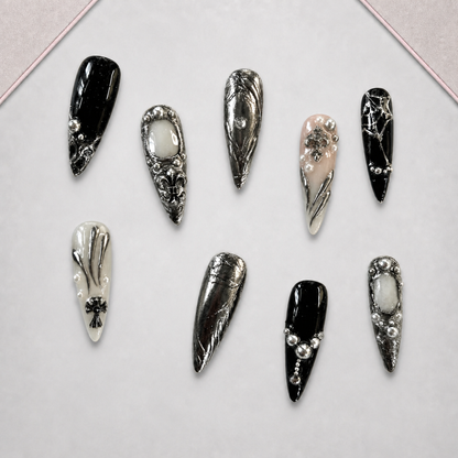 Chrome Reliquary press-on nail set arranged on a display tray with glossy black and ornate silver gothic designs.