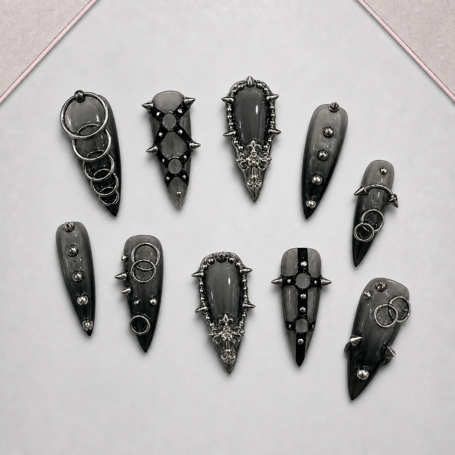 Iron Reliquary press-on nail set displayed on an approved tray, showing varied dark gothic ring, stud, and spike motifs.