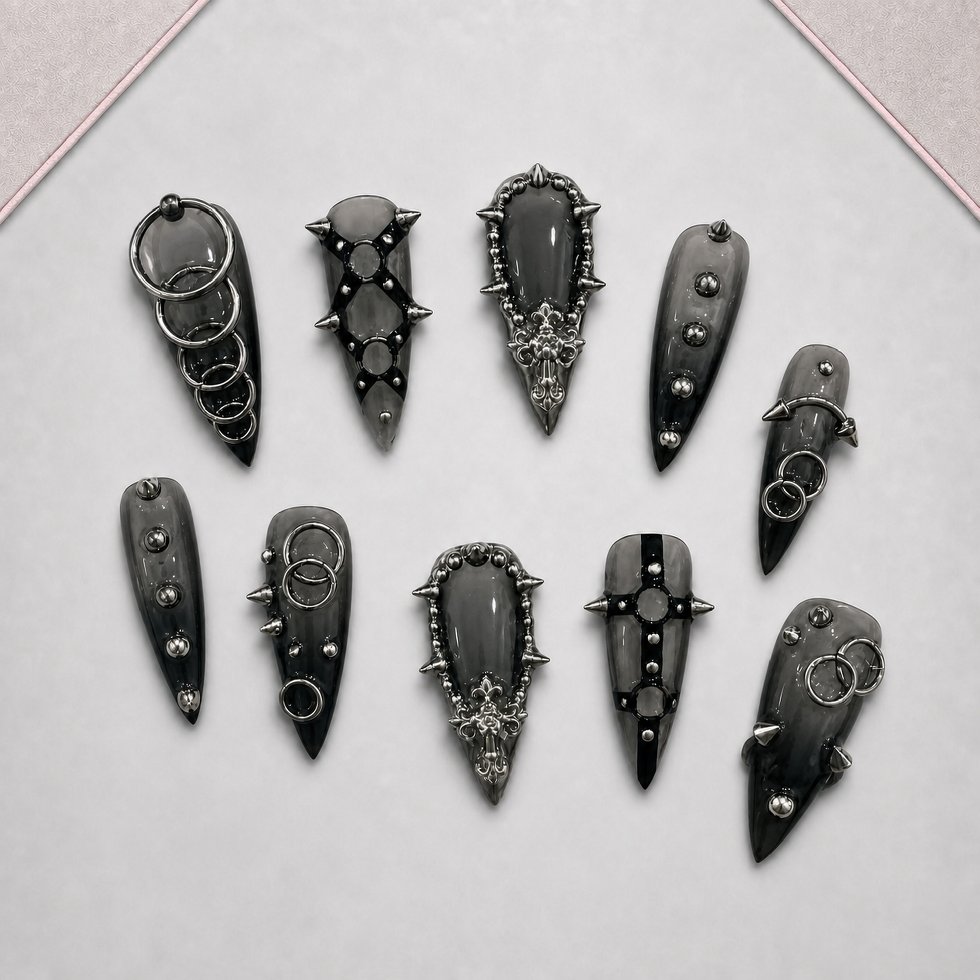 Iron Reliquary press-on nail set displayed on an approved tray, showing varied dark gothic ring, stud, and spike motifs.