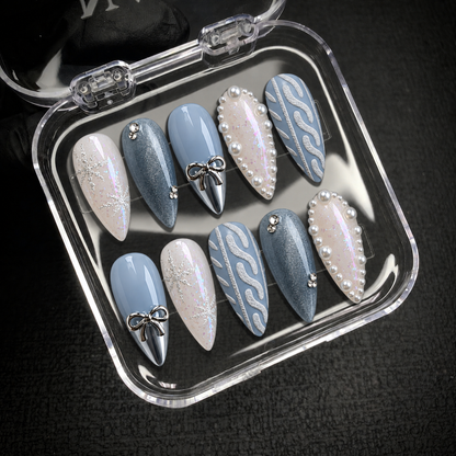 Open clear case displaying ten coordinated Frosted Blue Bow nails against a dark background.