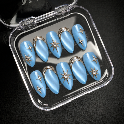 Ten blue starburst nails arranged inside an open clear case against a dark background.