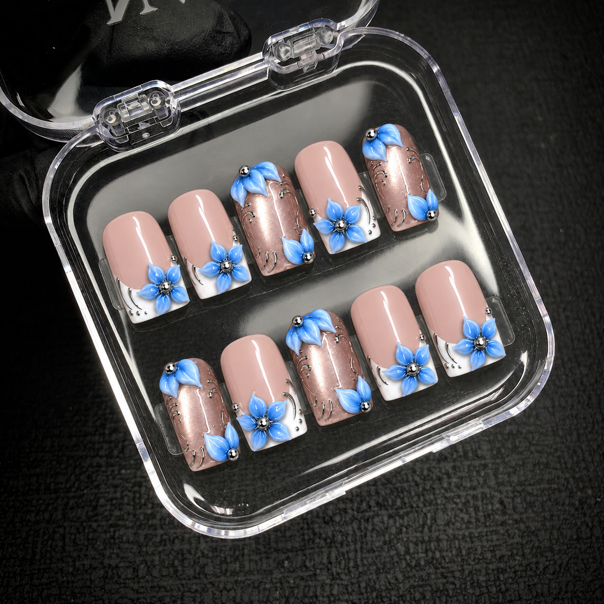 Ten Frosted Blue Petals nails displayed inside an open clear case against a dark background, showing blue flowers and rose-toned accent nails.