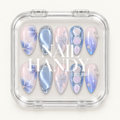 Closed clear case displaying ten pink and icy blue winter nails beneath white Nail Handy lettering on the lid.
