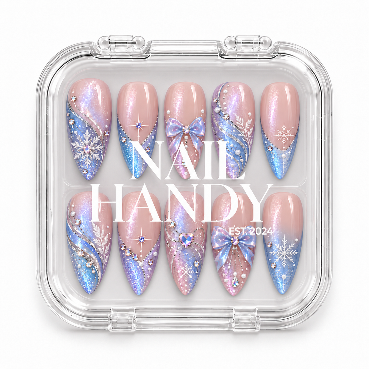 Closed clear case displaying ten pink and blue winter nails beneath white Nail Handy lettering, with bow accents, snowflakes, and faceted gems visible through the lid.