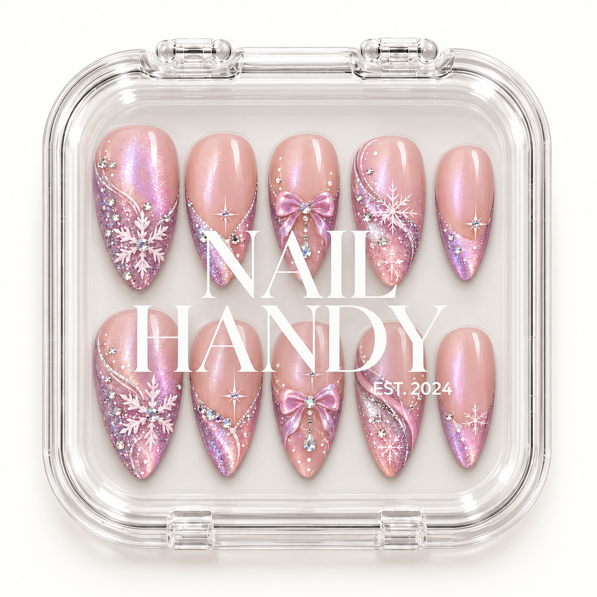 Closed clear Nail Handy case displaying ten blush pink nails with snowflakes, bows, lavender shimmer, and gem accents beneath white lid lettering.