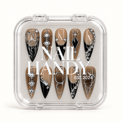 Closed clear Nail Handy case displaying ten taupe and black nails with silver-tone thorn-like designs beneath white branding.