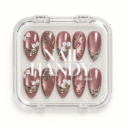Closed clear Nail Handy case displaying ten mauve shimmer nails in two rows, with white floral accents, silver-toned ornament, and gem details.