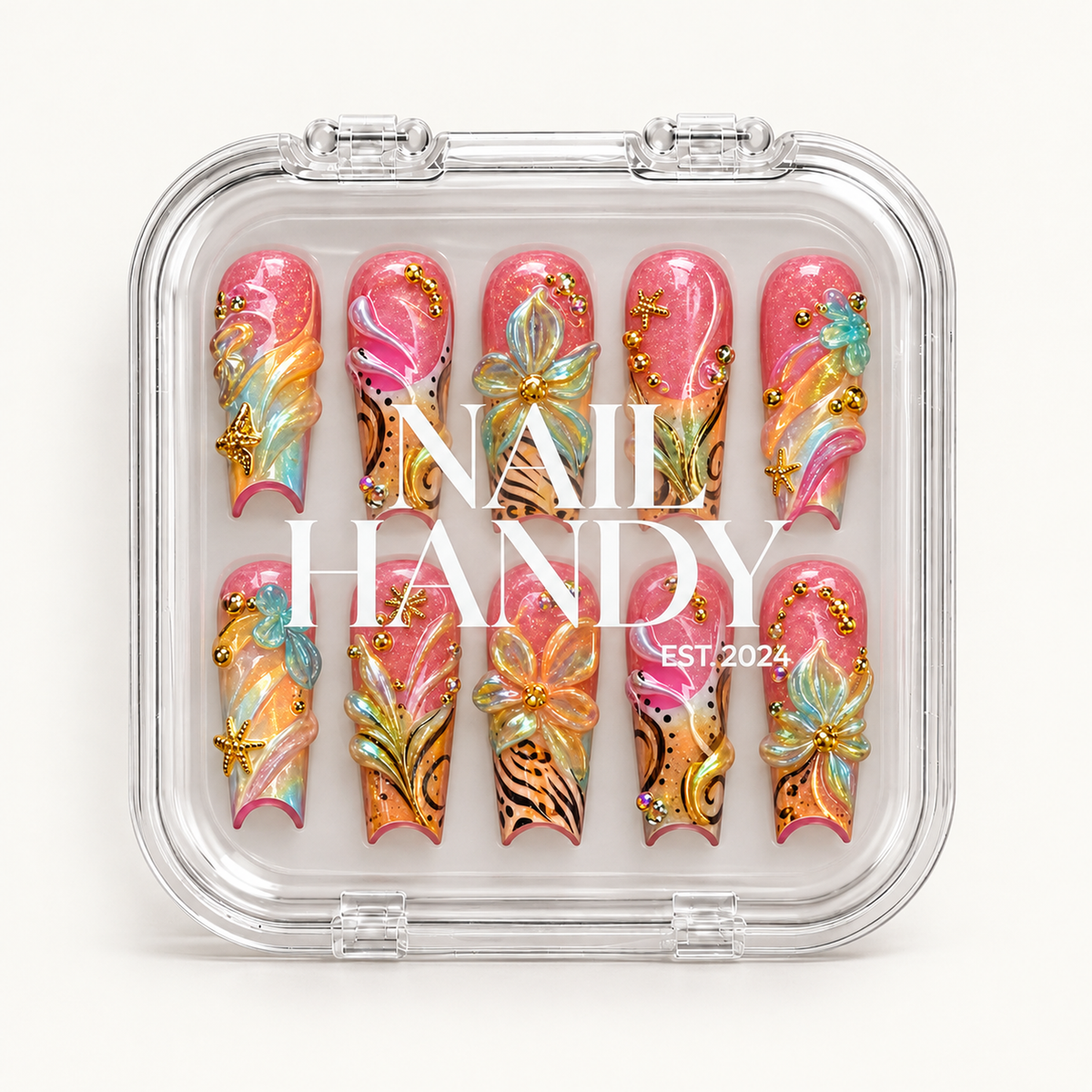 Closed clear case with white lettering displaying ten coral-pink and peach nails decorated with dimensional flowers, aqua swirls, black patterns, and gold-toned accents.