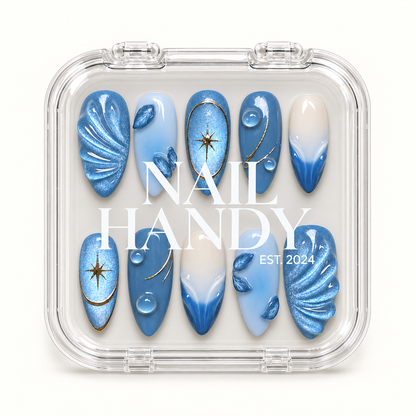 Clear Nail Handy case displaying ten blue and white nails with shimmering folds, leaves, gold stars, and gradient accents.
