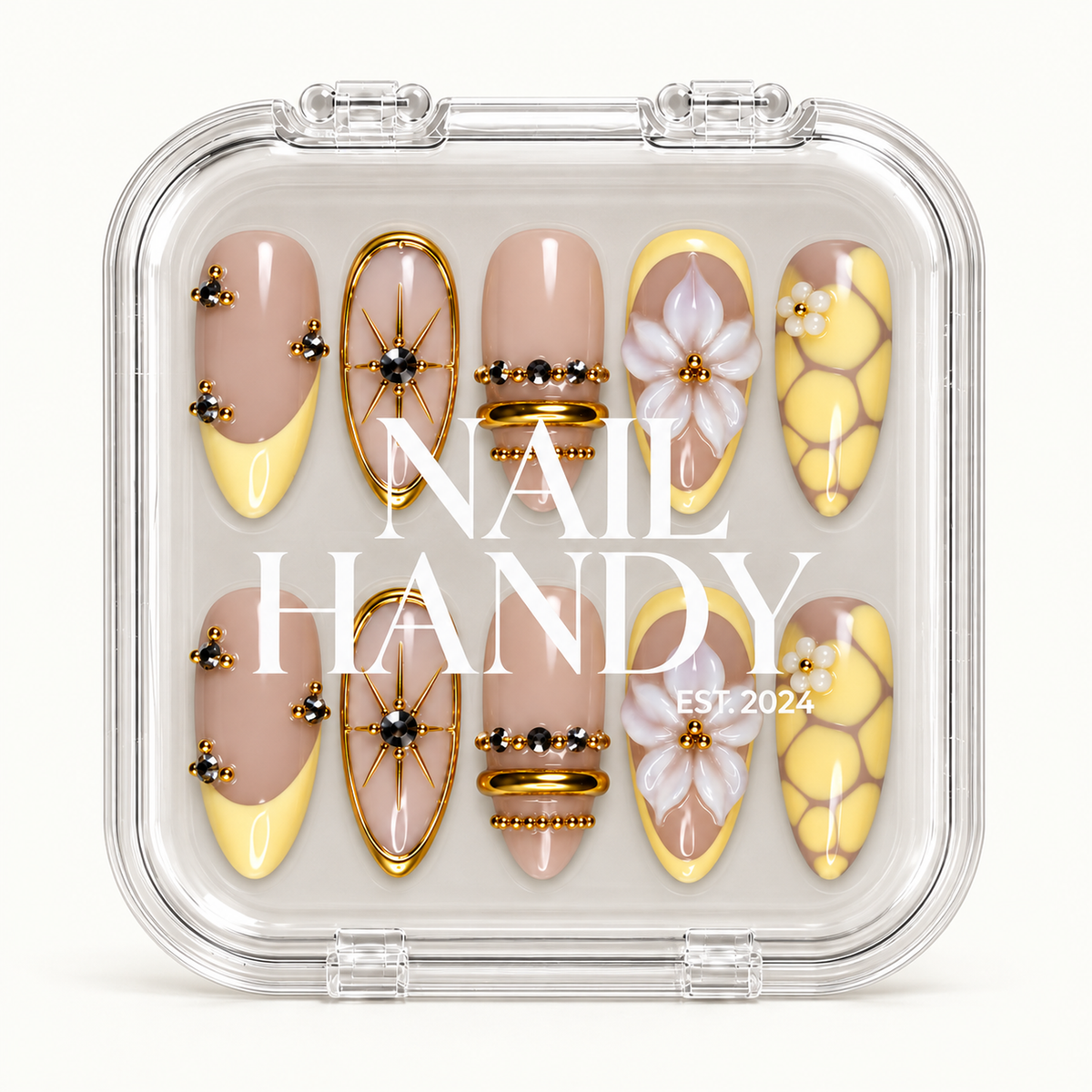 Closed clear case with white Nail Handy lettering, displaying ten yellow and nude nails with floral, starburst, and gold-tone bead accents.