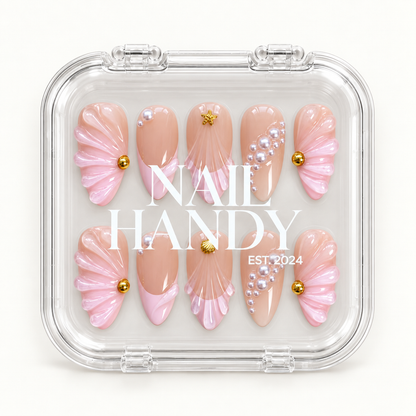 Closed clear Nail Handy display box showing ten nude blush and pink nails with raised shell fans, pearl-like embellishments, and gold-tone accents.