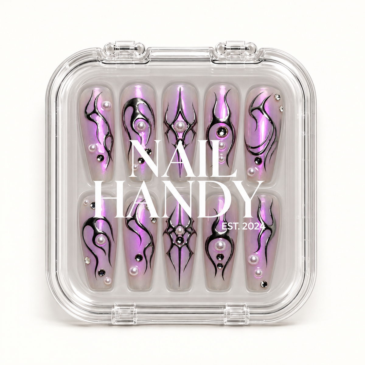 Closed clear Nail Handy case displaying ten lilac nails with black sigil artwork, pearl-like accents, and reflective gems beneath white lid lettering.