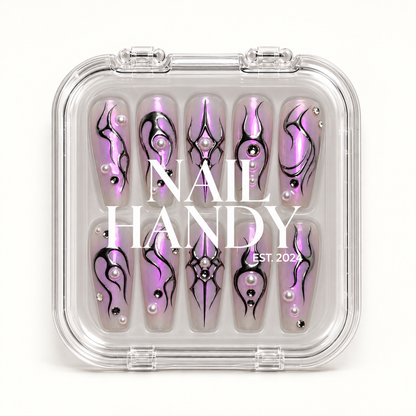 Closed clear Nail Handy case displaying ten lilac nails with black sigil artwork, pearl-like accents, and reflective gems beneath white lid lettering.