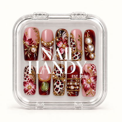 Closed clear case with white Nail Handy lettering, displaying ten coordinated burgundy and blush nails with flowers, leopard spots, and pearl-like accents.