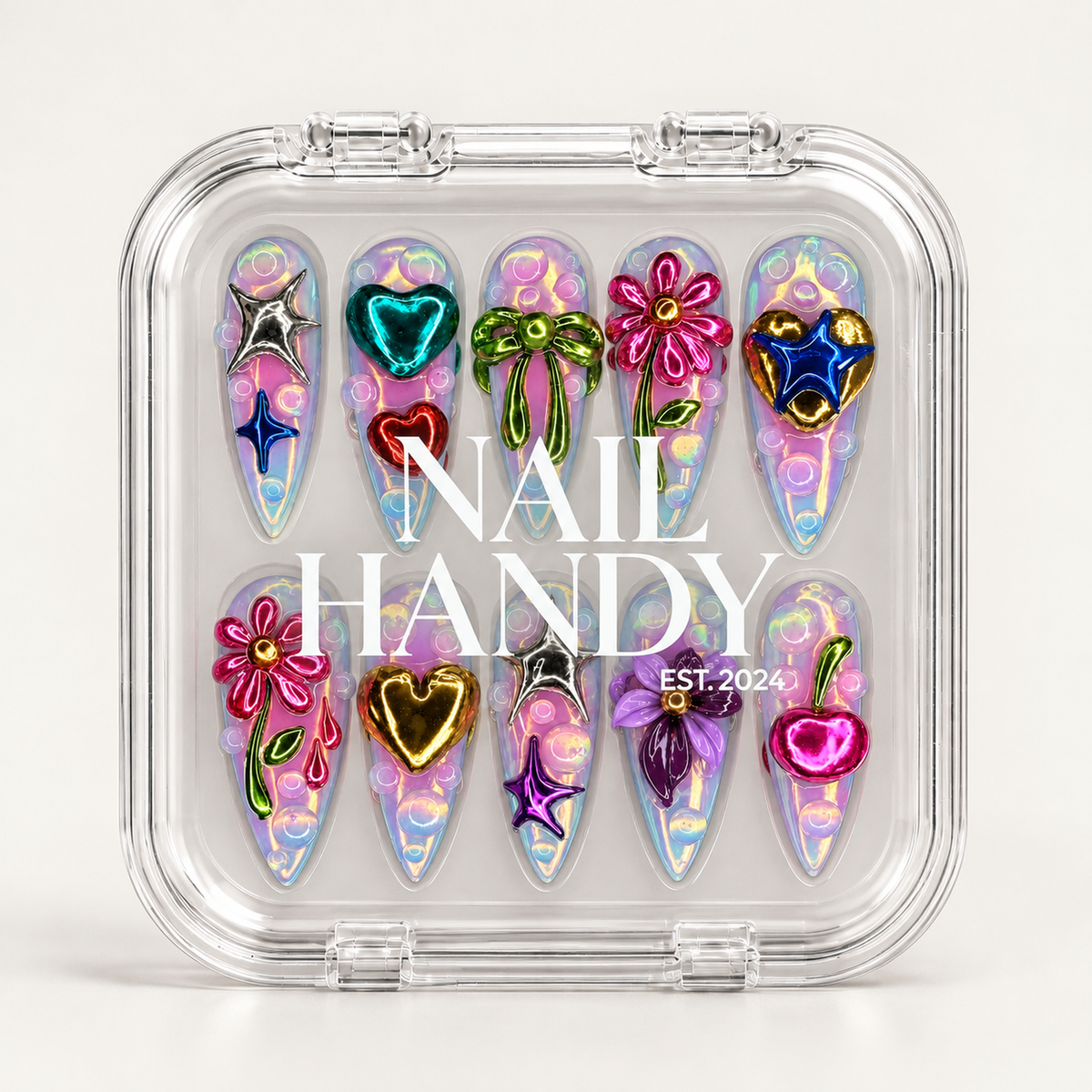 Closed clear Nail Handy case displaying ten pastel iridescent nails with raised colorful motifs beneath white branding on the lid.