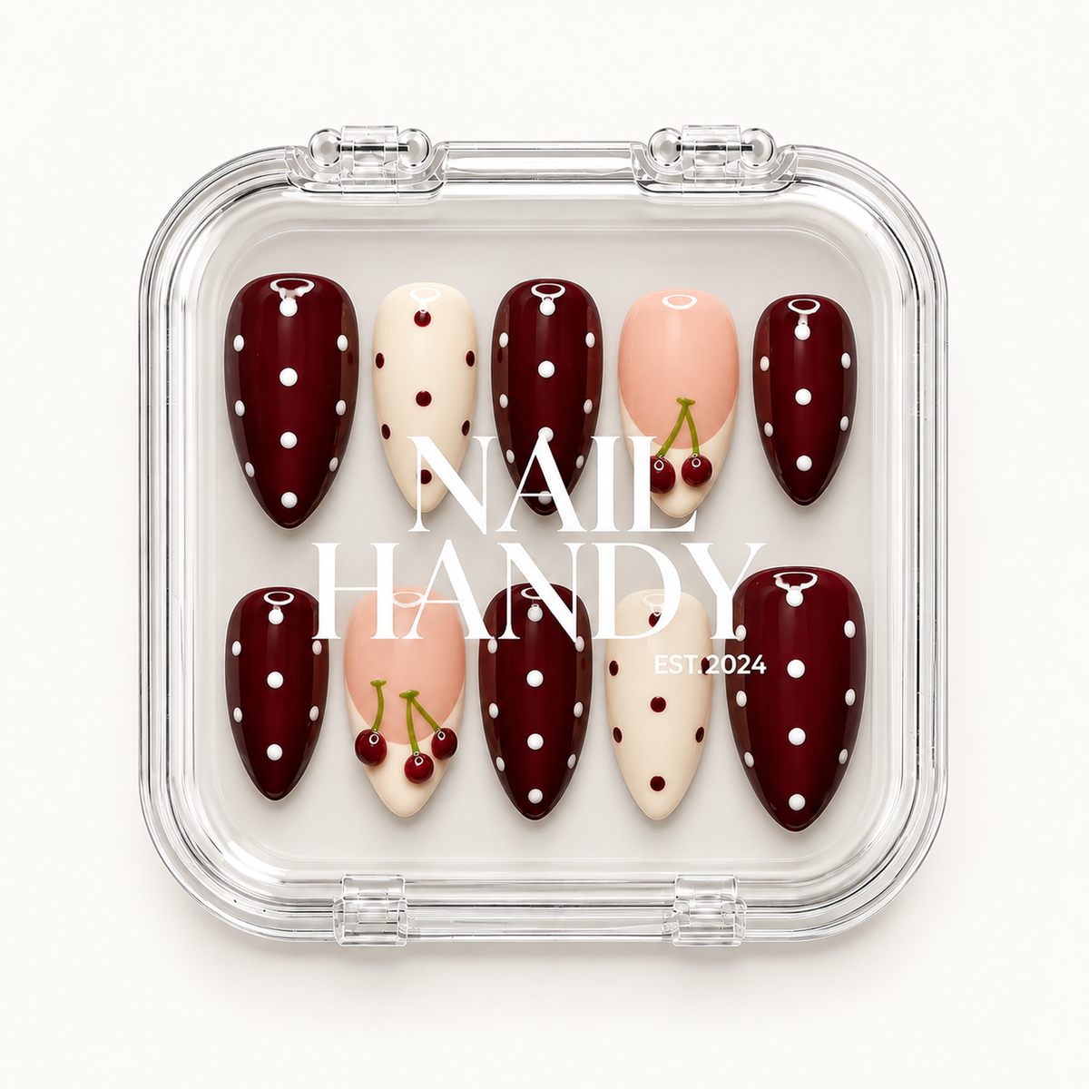 Closed clear case with white Nail Handy lettering displaying ten burgundy polka dot, ivory dotted, and blush pink cherry accent nails.