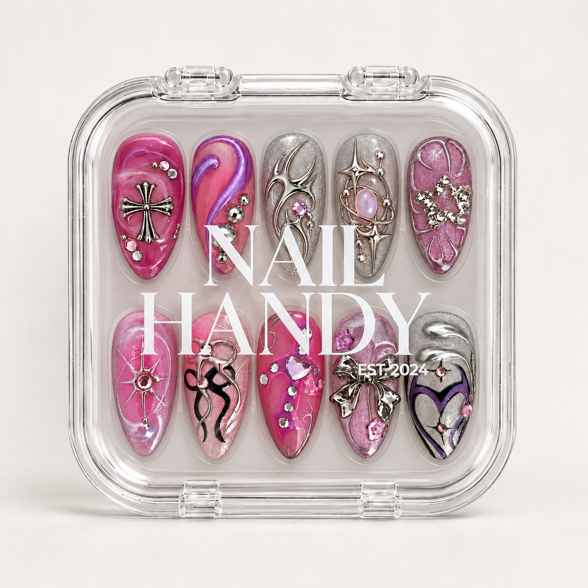 Closed clear case displaying ten coordinated decorated nails beneath white Nail Handy lettering on a light background.