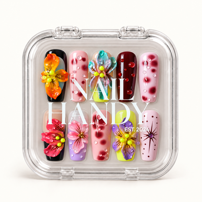 Closed clear case with white Nail Handy lettering displaying ten colorful floral and spotted nails arranged in two rows.
