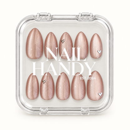 Closed clear Nail Handy case displaying ten blush-nude shimmer nails with silver-toned heart accents beneath white branding on the lid.