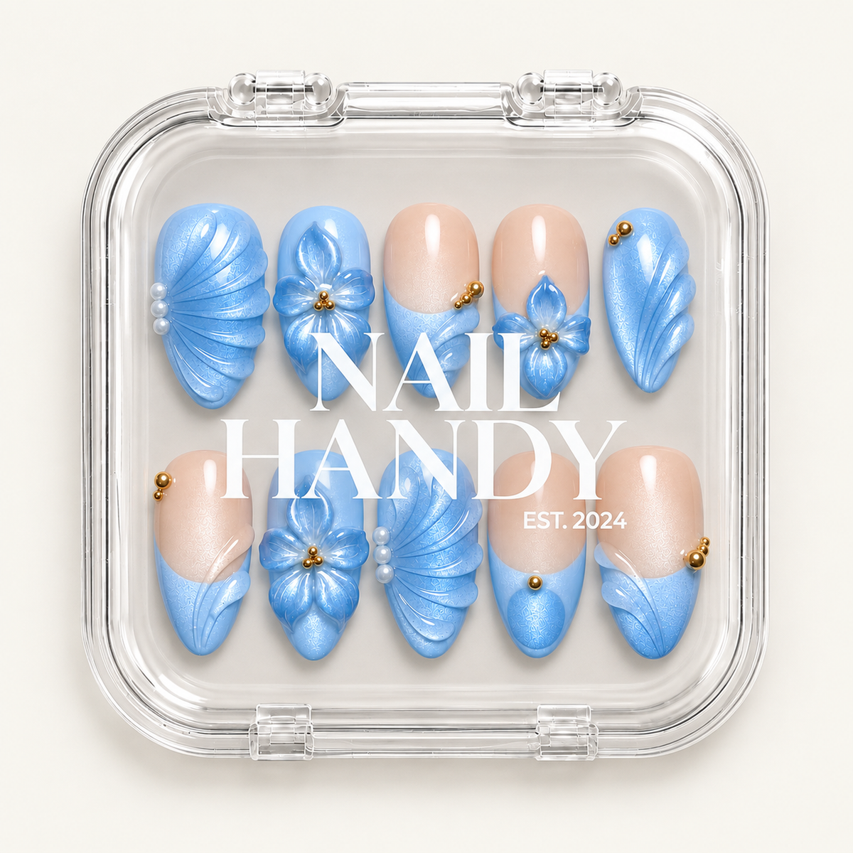 Clear Nail Handy case displaying ten pale blue and nude press-on nails with floral and fan-like details.