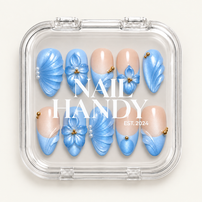 Clear Nail Handy case displaying ten pale blue and nude press-on nails with floral and fan-like details.