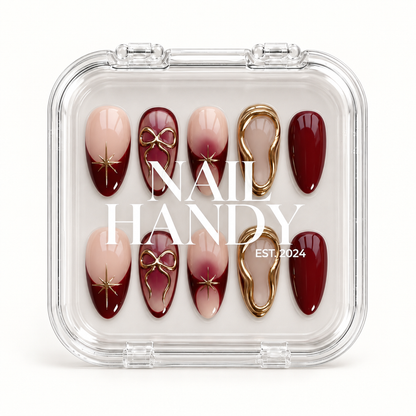Closed clear Nail Handy case displaying ten burgundy and blush nude nails with gold bows, starbursts, and irregular gold borders.