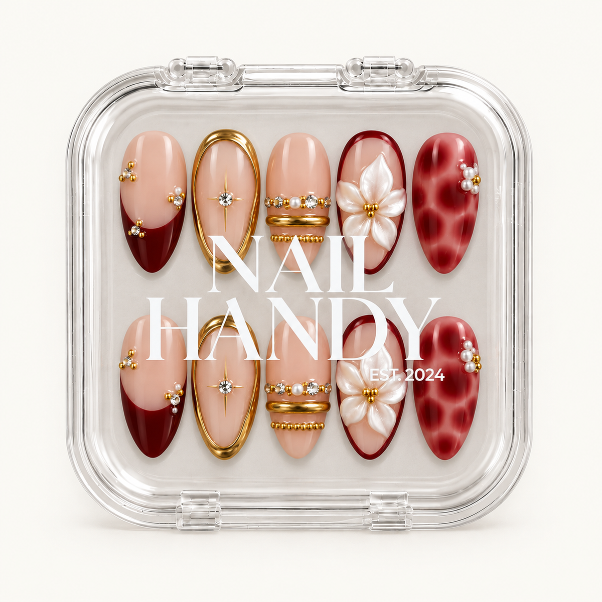 Closed clear Nail Handy case displaying ten blush pink and deep red nails with white flowers, gold-tone details, and pearl-like accents.