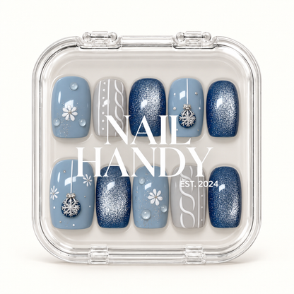 Closed clear case with white Nail Handy lettering displaying ten coordinated blue and gray winter nails with shimmer and decorative accents.