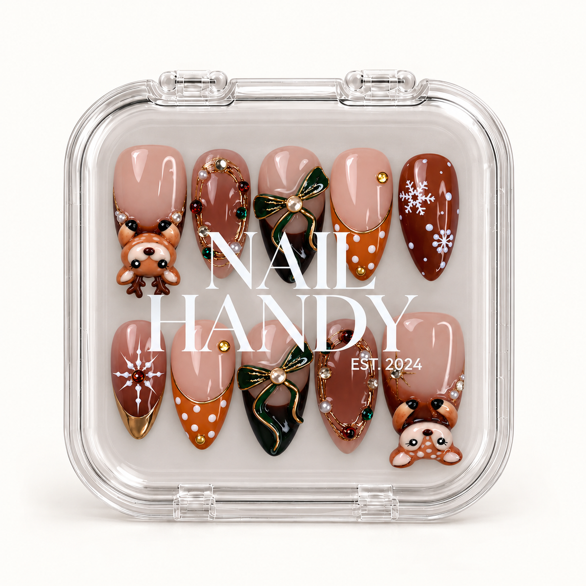 Closed clear case with white branding displaying ten Christmas nails decorated with reindeer, green bows, snowflakes, and gold-toned details.