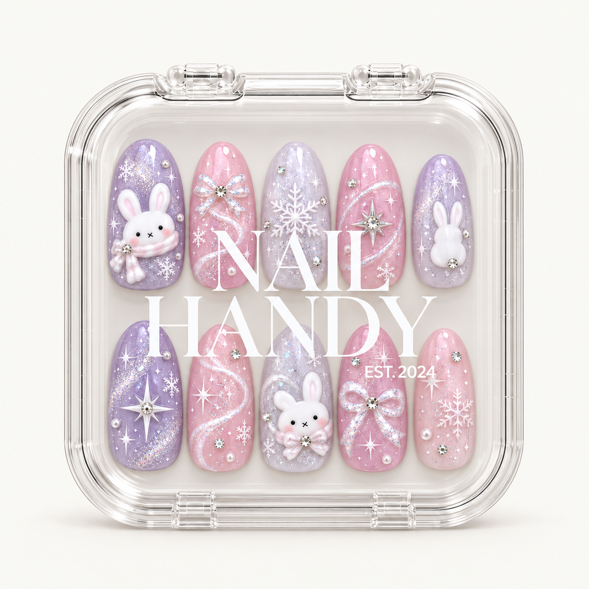 Closed clear case with white Nail Handy lettering displaying ten pink and lavender nails decorated with bunnies, snowflakes, bows, and shimmering accents.