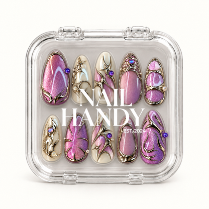 Closed clear Nail Handy case displaying ten pink-lilac shimmer and ivory nails with metallic detailing beneath white lettering.